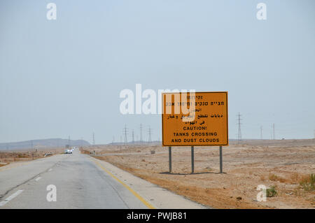 Warnschild in Hebräisch, Arabisch und Englisch Achtung! Tanks Crossing und Staubwolken. In der Wüste Negev, Israel auf dem Weg nach Eilat fotografiert. Stockfoto