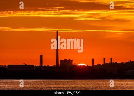 Whitegate, Cork, Irland, Juli 2017 18. Whitegate Ölraffinerie und der ESB in Aghada Silhouette von der aufgehenden Sonne in Cork harbou Stockfoto