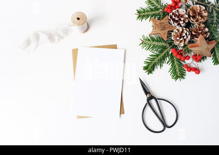 Weihnachten Komposition. Leere Grußkarte, Umschlag Mock-up-Szene. Dekorative Ecke. Tannenzapfen, Fir Tree Branches, rote Vogelbeeren und Holz- Sta Stockfoto