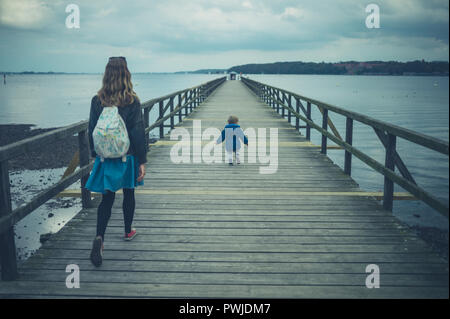 Ein Kind und seine Mutter sind zu Fuß auf einem Pier im Herbst