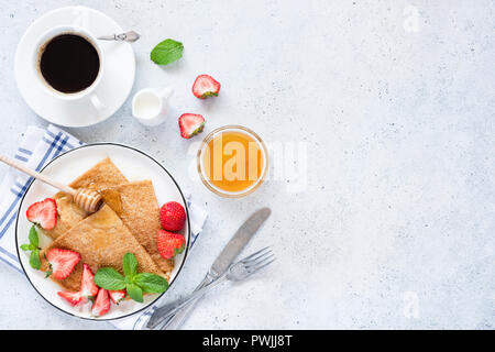 Französische Crepes oder Blini mit Erdbeeren, Honig und Tasse Kaffee auf Tisch. Ansicht von oben und kopieren Sie Platz für Text, Rezeptur oder Restaurant Cafe Menü Stockfoto