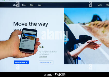 Moskau, Russland - Oktober 16, 2018: Die home Internet Seite der mobilen Anwendung Uber.com auf dem Bildschirm, um das Smartphone in männlicher Hand auf einem gegen Th Stockfoto
