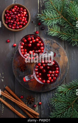 Cranberry Drink auf Holz- Hintergrund dekoriert mit Tannenzweigen, Gewürzen und frischen Beeren Stockfoto