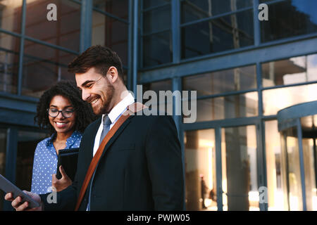 Zwei Kollegen aus Bürogebäude mit einem digitalen Tablet. Kaufmann und Frau zusammen mit digitalen Tablet. Stockfoto