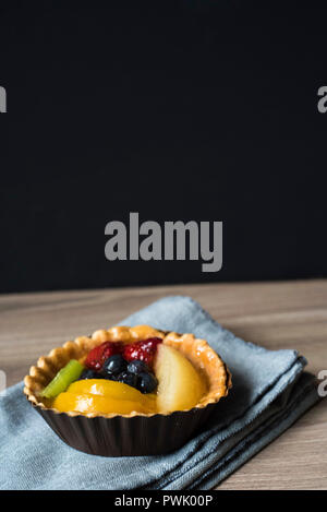 Frisches Obst Tartlette ruht in seiner Wrapper auf einem Tuch Serviette bereit zu Essen für ein Dessert oder Snack Stockfoto