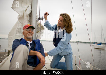 Portrait eines älteren Erwachsenen Mann neben seiner Frau winching ein Segel auf einem Boot sitzen. Stockfoto