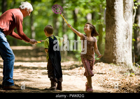 Großvater mit seinen Enkelkindern im Wald Stockfoto