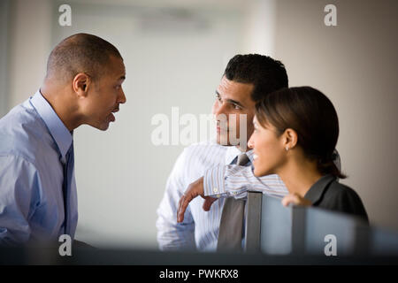 Mitte - Erwachsene Unternehmer im Gespräch mit zwei seiner Kollegen in einem Büro. Stockfoto