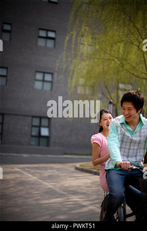 Junge erwachsene Paare auf einem Fahrrad an einem Park. Stockfoto