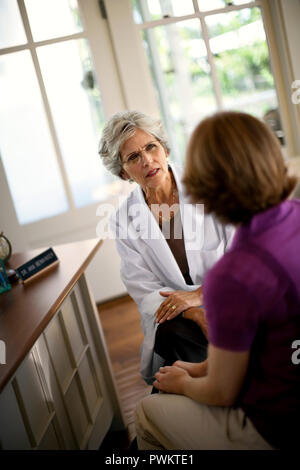 Reife weibliche Arzt schaut besorgt, da sie Gespräche mit ihren Patienten. Stockfoto