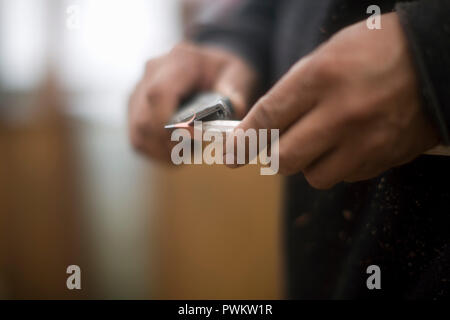 Nahaufnahmen der Hände des Menschen schärfen ein Bleistift mit einem Messer Stockfoto