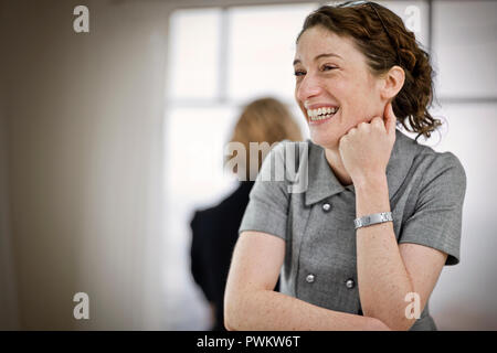 Lachende junge Frau ihr Kinn auf ihre Hand. Stockfoto