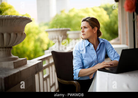 Geschäftsfrau, draußen auf dem Balkon mit einem Laptop. Stockfoto