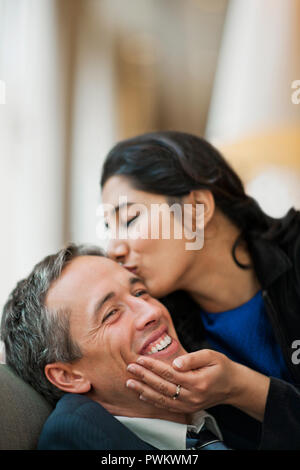 Grinsend junge Unternehmer erhält einen Kuss auf die Wange von einem hübschen weiblichen business Kollege. Stockfoto