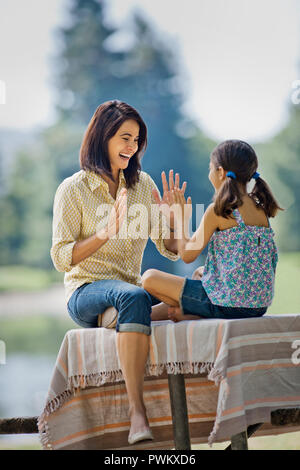 Glückliche Mutter und Tochter spielen eine Hand im Park. Stockfoto