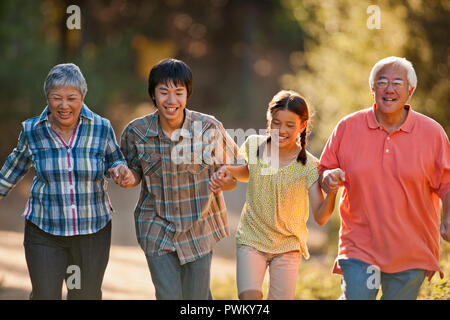 Lächelnd senior Paar Arm in Arm mit ihren Enkelkindern. Stockfoto