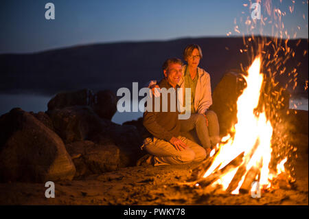 Lächelnd Mann und Frau mit einem Lagerfeuer am Strand. Stockfoto