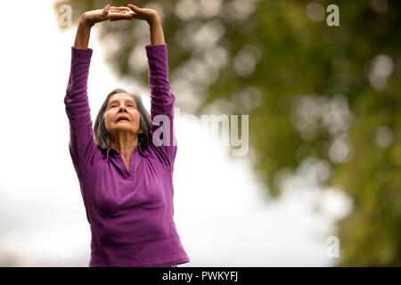 Ältere Frau Yoga in Ihrem Hinterhof. Stockfoto