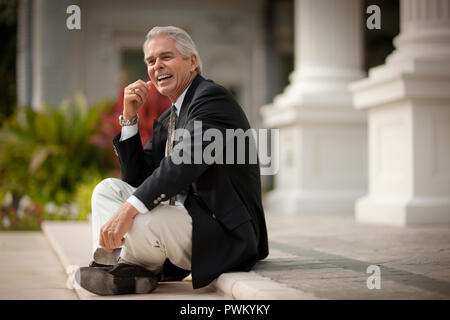 Lächelnd Geschäftsmann eine Pause auf den Stufen eines Gebäudes. Stockfoto