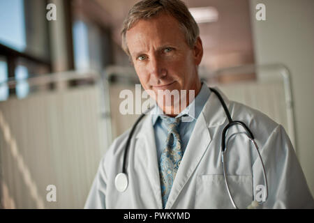 Porträt einer stattlichen im mittleren Alter Arzt tragen ein Stethoskop um den Hals. Stockfoto