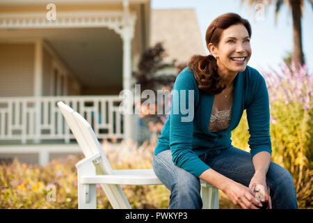 Reife Frau genießt Glas Rotwein in Ihrem Hinterhof. Stockfoto