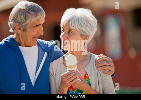 Gerne ältere Frau an ihren Mann suchen, als sie ein Eis hält. Stockfoto