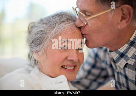 Lächelnd senior Frau Kuss auf die Stirn, die von ihrem Ehemann. Stockfoto