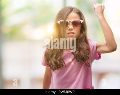 Brunette hispanische Mädchen tragen Sonnenbrillen genervt und frustriert schrie mit Zorn, verrückt und schreien mit erhobener Hand, Wut Konzept Stockfoto