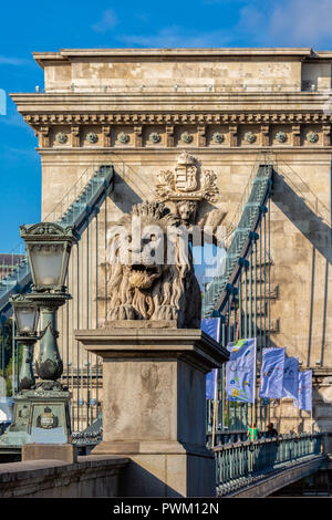 Laterne und Skulptur eines Löwen auf dem Hintergrund der Bogen der Kettenbrücke über die Donau in Budapest. Stockfoto