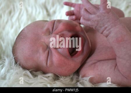 Neugeborenes Baby weinen auf einem weißen fuzzy Decke Stockfoto