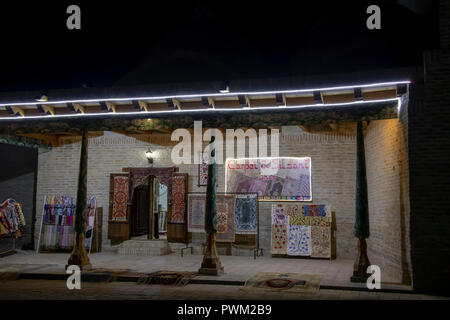 Buchara, Usbekistan - September 23, 2018: saye und Teppich Shop in Basar bei Nacht beleuchtet in Buchara, Usbekistan. Stockfoto