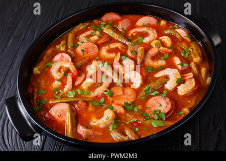 Ansicht von oben der Köstlichen Gumbo mit Garnelen, Würstchen in einem holländischen Ofen auf einem Schwarzen Tisch, horizontale Ansicht von oben, close-up Stockfoto