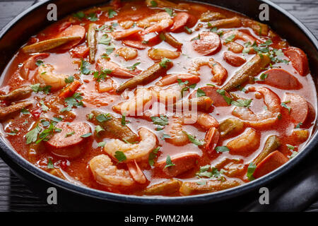 Ansicht von oben der Köstlichen Gumbo mit Garnelen, Würstchen in einem holländischen Ofen auf einem Schwarzen Tisch, horizontale Ansicht von oben, close-up Stockfoto