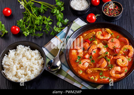 Ansicht von oben der Köstlichen Gumbo mit Garnelen, Okra und Würstchen in einer Schüssel auf einem Schwarzen Tisch serviert mit Schale, weißer Reis, Ansicht von oben, close-up Stockfoto