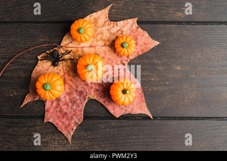 Herbst Halloween Dekoration Konzept mit trockenen Maple Leaf, fake Kürbisse und kleine schwarze Spinne auf Holz- Hintergrund mit Kopie Raum, flach Stockfoto