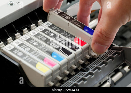 Mann Ersetzen einer Tintenpatrone auf eine Farbe tintenstrahldrucker (Nahaufnahme) - USA Stockfoto