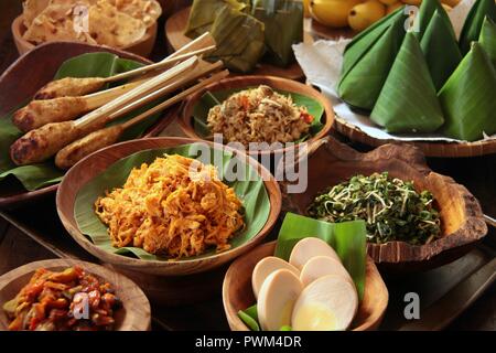 Nasi Jinggo, die Balinesische kleine Mahlzeit aus Reis mit gebratenen Nudeln, Gemüse und Ei umhüllt mit Banana Leaf; mit zusätzlichen optionalen Beilagen serviert. Stockfoto