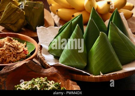 Nasi Jinggo, die Balinesische kleine Mahlzeit aus Reis mit gebratenen Nudeln, Gemüse und Ei umhüllt mit Banana Leaf; mit zusätzlichen optionalen Beilagen serviert. Stockfoto