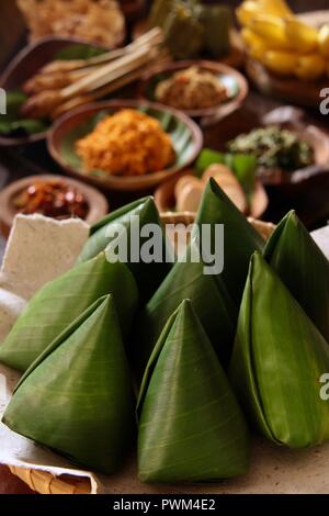 Nasi Jinggo, die Balinesische kleine Mahlzeit aus Reis mit gebratenen Nudeln, Gemüse und Ei umhüllt mit Banana Leaf; mit zusätzlichen optionalen Beilagen serviert. Stockfoto