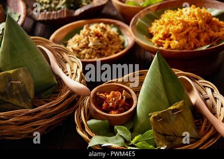 Nasi Jinggo, die Balinesische kleine Mahlzeit aus Reis mit gebratenen Nudeln, Gemüse und Ei umhüllt mit Banana Leaf; mit zusätzlichen optionalen Beilagen serviert. Stockfoto