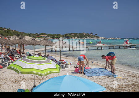 Ein paar Entfaltung eine Decke auf dem Strand. Strand von Santa Giulia in Korsika. Plaża Santa Giulia na Korsyce. Para rozkłada Koc na plaży. Stockfoto