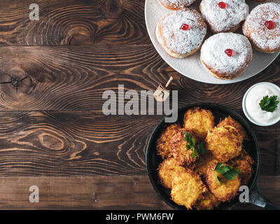 Jüdische Feiertag Hanukkah Konzept und Hintergrund. Hanukkah food Donuts und Kartoffeln Pfannkuchen latkes, Öl und traditionellen spinnig dreidl auf hölzernen Tisch. Top View oder flach. Kopieren Sie Platz für Text. Stockfoto