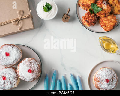 Jüdische Feiertag Hanukkah Konzept und Hintergrund. Hanukkah food Donuts und Kartoffeln Pfannkuchen latkes, Öl, Kerzen, Geschenkbox und traditionellen spinnig dreidl. Top View oder flach. Kopieren Sie Platz für Text Stockfoto