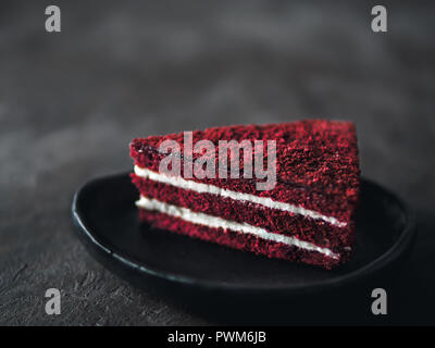 Stück Red Velvet Cake mit perfekten Textur in matt Platte auf schwarz Tischplatte. Scheibe der köstlichen hausgemachten Red Velvet Cake mit Himbeeren und Schokolade. Kopieren Sie Platz für Text. Stockfoto