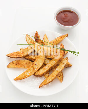 Potato Wedges gesichert mit Paprika, bestreut mit Meersalz und Schnittlauch, Tomatensauce auf Seite Stockfoto