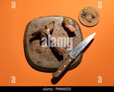 Die Reste eines T-Bone Steak auf einem Holzbrett Stockfoto