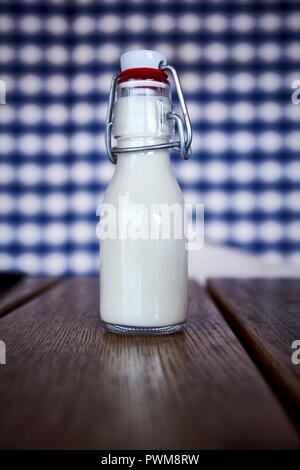 Eine kleine Flasche Milch auf einem Holztisch Stockfoto
