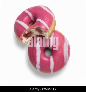 Zwei rosa Erdbeere Donuts mit Erdbeermarmelade gefüllt, eine mit einem Bissen genommen Stockfoto