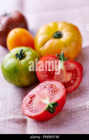 Verschiedenen farbigen Tomaten auf eine Leinwand, eine halbiert Stockfoto