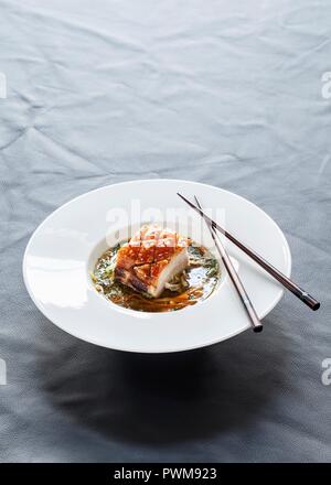 Schweinebauch in einem Zitronengras und Koriander Bouillon mit Gemüsestreifen und Kräuter Stockfoto